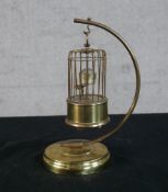 A 19th/early 20th century brass automaton clock in the form a bird in a birdcage, raised on circular
