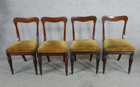 A set of four Victorian mahogany framed bar back dining chairs with stuffover seats raised on turned