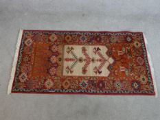 A modern red ground woollen rug, the central ivory field with tree of life design with geometric
