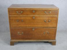A 19th century oak chest of three graduating drawers with brass swing handles raised on shaped
