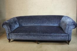 A late Victorian mahogany framed blue upholstered scroll arm settee raised on turned bun feet and