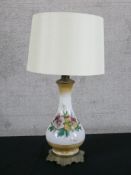 An early 20th century painted milk glass baluster shaped table lamp decorated with flowers, raised