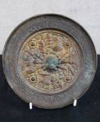 A 19th century Chinese cast brass circular mirror, embossed with various objects within a scroll