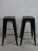 A contemporary pair of square black painted metal stacking stools raised on splayed supports.