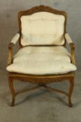 A Louis XV style walnut framed open armchair with bergere back, raised on carved cabriole supports