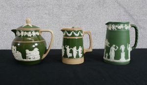 A collection of green Wedgwood Jasperware made up of a tankard and two jugs with metal lids. Stamped
