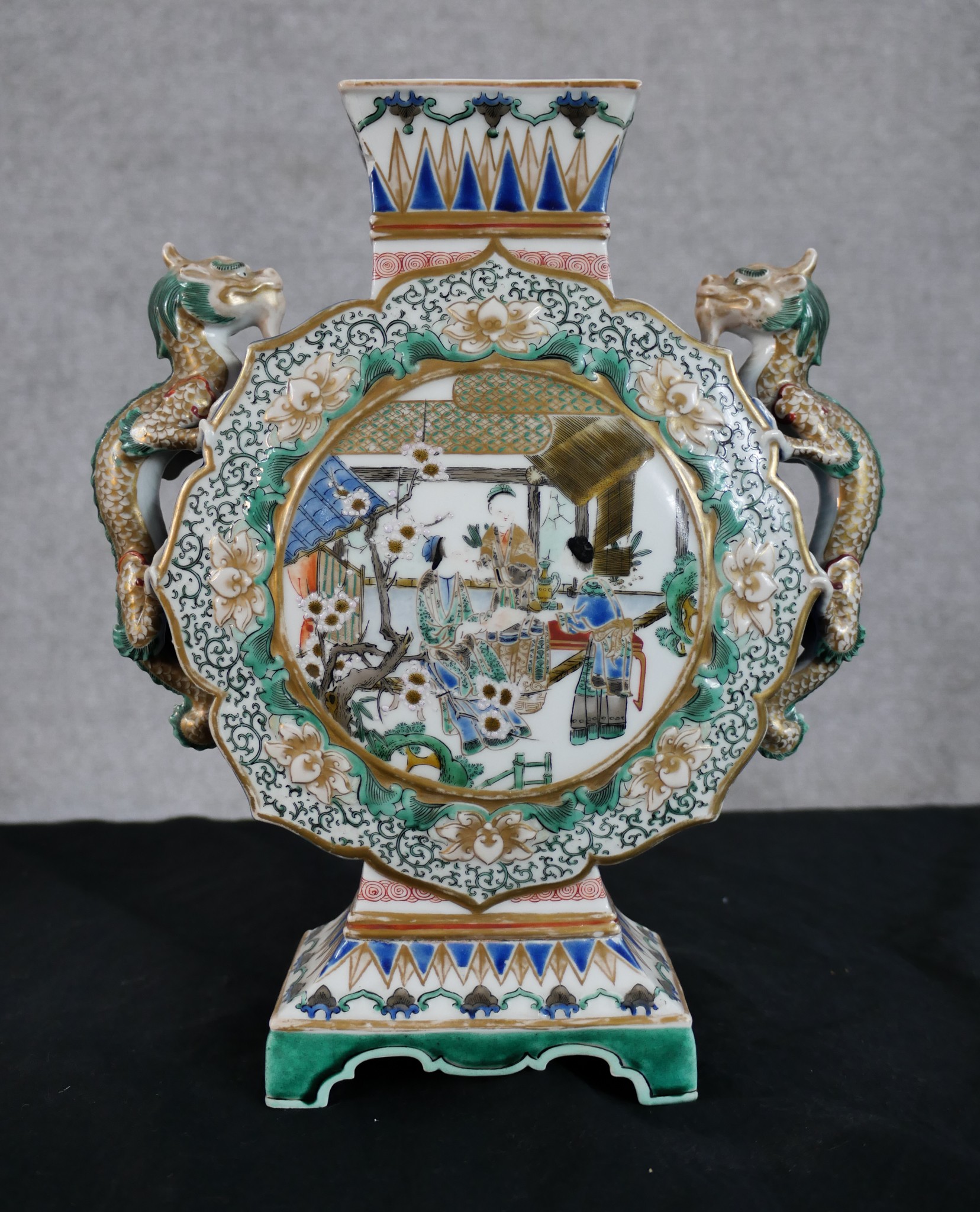 A decorative Chinese vase depicting a rural scene and two dragons as handles. With the artist's seal
