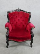 A 19th century ebonised framed deep button back upholstered wingback chair raised on carved cabriole