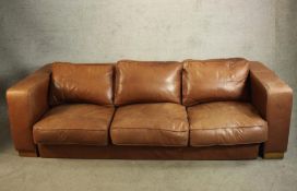 A contemporary brown leather three seater settee raised on beech block supports. H.66 W.239 W.99cm.