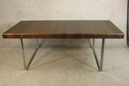 A large contemporary mahogany effect topped dining table raised on square chrome plated supports.