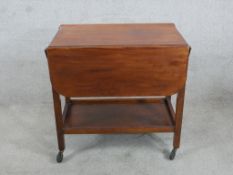 A mid 20th century mahogany drop flap two tier trolley raised on square supports terminating in
