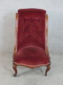 A 19th century carved mahogany show framed upholstered button back nursing chair raised on carved