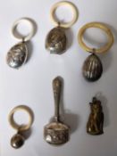 A collection of silver, brass and bone children's rattles, each with a different design.