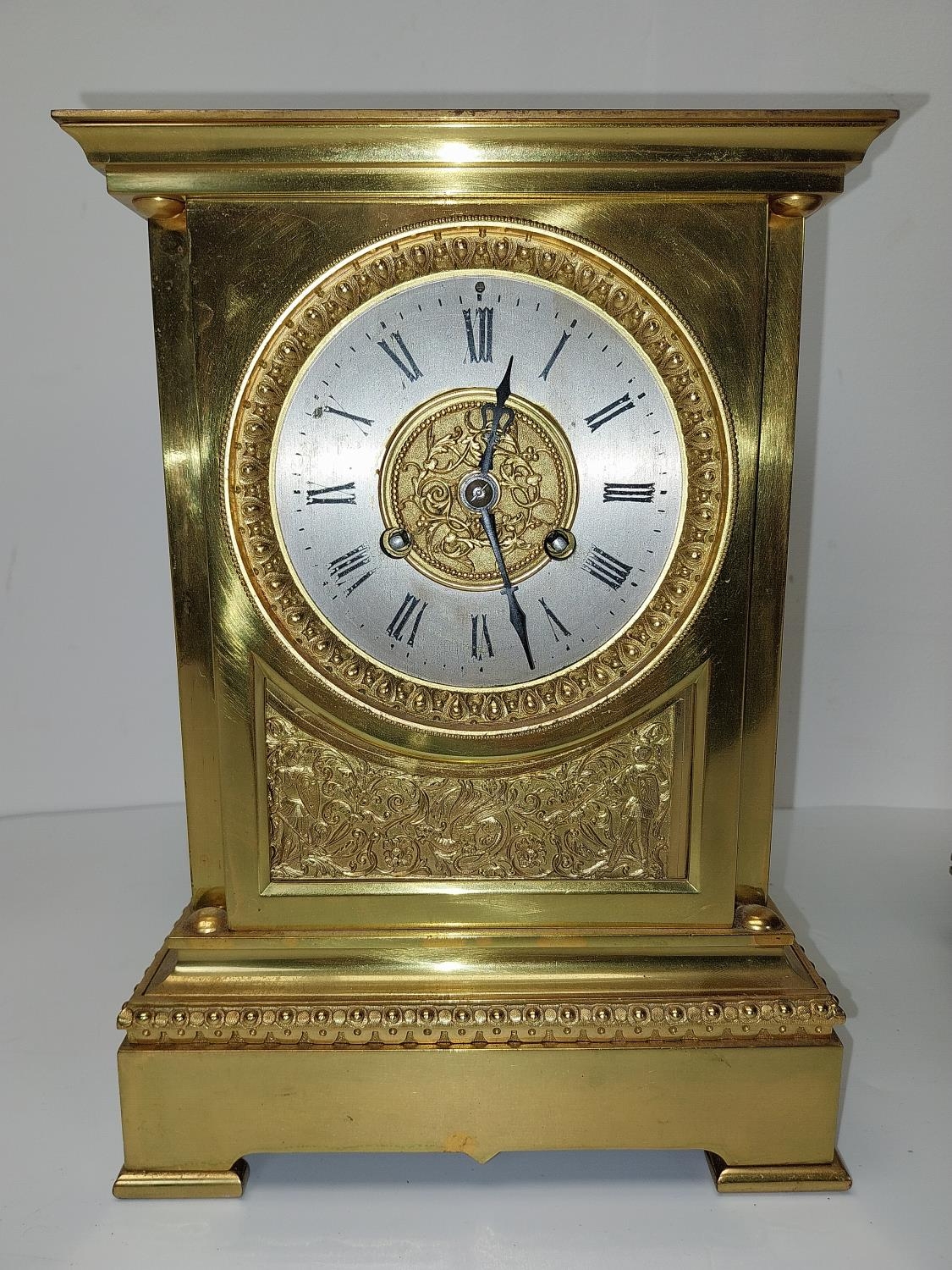 An early 20th century brass mantle clock with relief scrolling foliate and knight design, classical