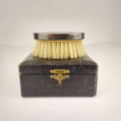 A leather cased silver travel brush.
