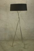 A minimalist style floor lamp with a black shade sitting on a chrome tripod. H.163cm.