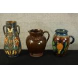 Three studio pottery jugs. Two with a floral decoration. H.30cm (largest).