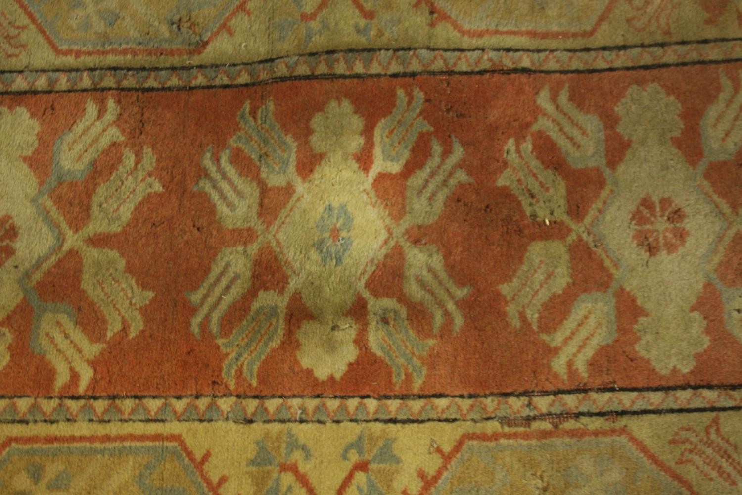 A Persian rug with repeating floral medallions on a terracotta ground. L.146 W.84cm.
