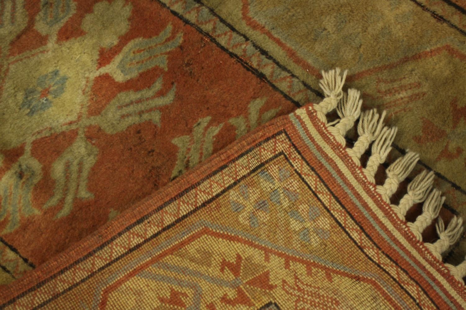 A Persian rug with repeating floral medallions on a terracotta ground. L.146 W.84cm. - Image 3 of 3