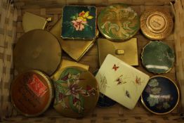 A collection of fourteen makeup compacts. One in the shape of a fan with with a Chinese design