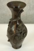 A Meiji period Japanese bronze vase with coiling relief dragon breathing fire, fluted rim and raised