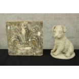 A stone carved fleur-de-lis and and composite dog figure. The fleur-de-lis with a weathered and aged