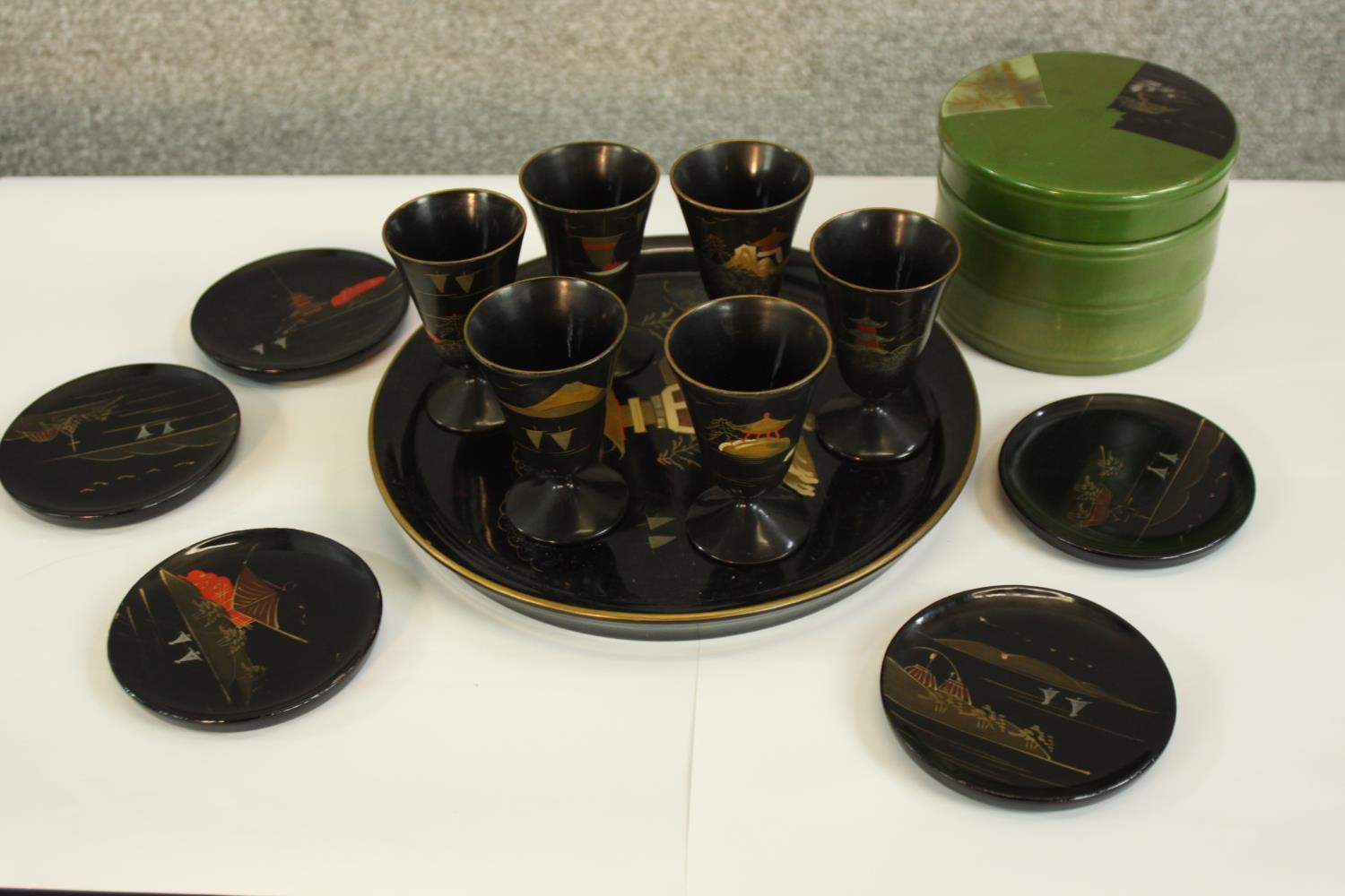 A Japanese lacquered set of six cups, a tray, five small plates housed in a round box. Each item