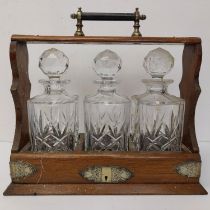 A 19th century oak and brass tantalus with three cut glass decanters.