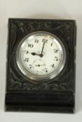 A Swiss made 8 day clock set in a pen rest with delicate floral relief. L.10 x W.8 cm.