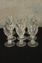 A set nine early 20th century faceted drinking glasses with central knop stem, raised on circular