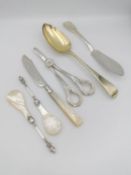 A collection of silver cutlery, including a later gilded Georgian serving spoon, a pair of grape