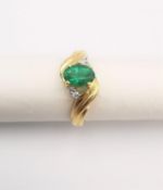 An 18ct yellow gold diamond and emerald cross over ring. Set to centre with an oval mixed cut