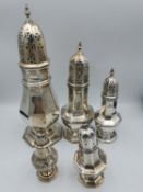 A collection of two pierced design sugar shakers along with three salt and pepper shakers. One