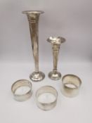 A collection of three silver napkin rings and two fluted vases. The vases with a weighted bases.