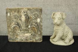 A stone carved fleur-de-lis and and composite dog figure. The fleur-de-lis with a weathered and aged