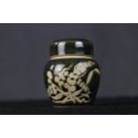 A Japanese ceramic lidded pot with deep green glaze and floral decoration. H.10 x W.9 x D.9 cm.