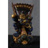 A Sri Lankan carved hardwood deity. Painted in a deep blue with gilt decoration. With beaked face