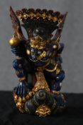 A Sri Lankan carved hardwood deity. Painted in a deep blue with gilt decoration. With beaked face