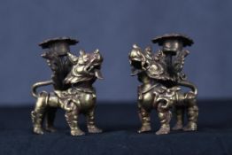 Two Chinese Foo dog or dragon gilt brass candle holders. Early twentieth century.