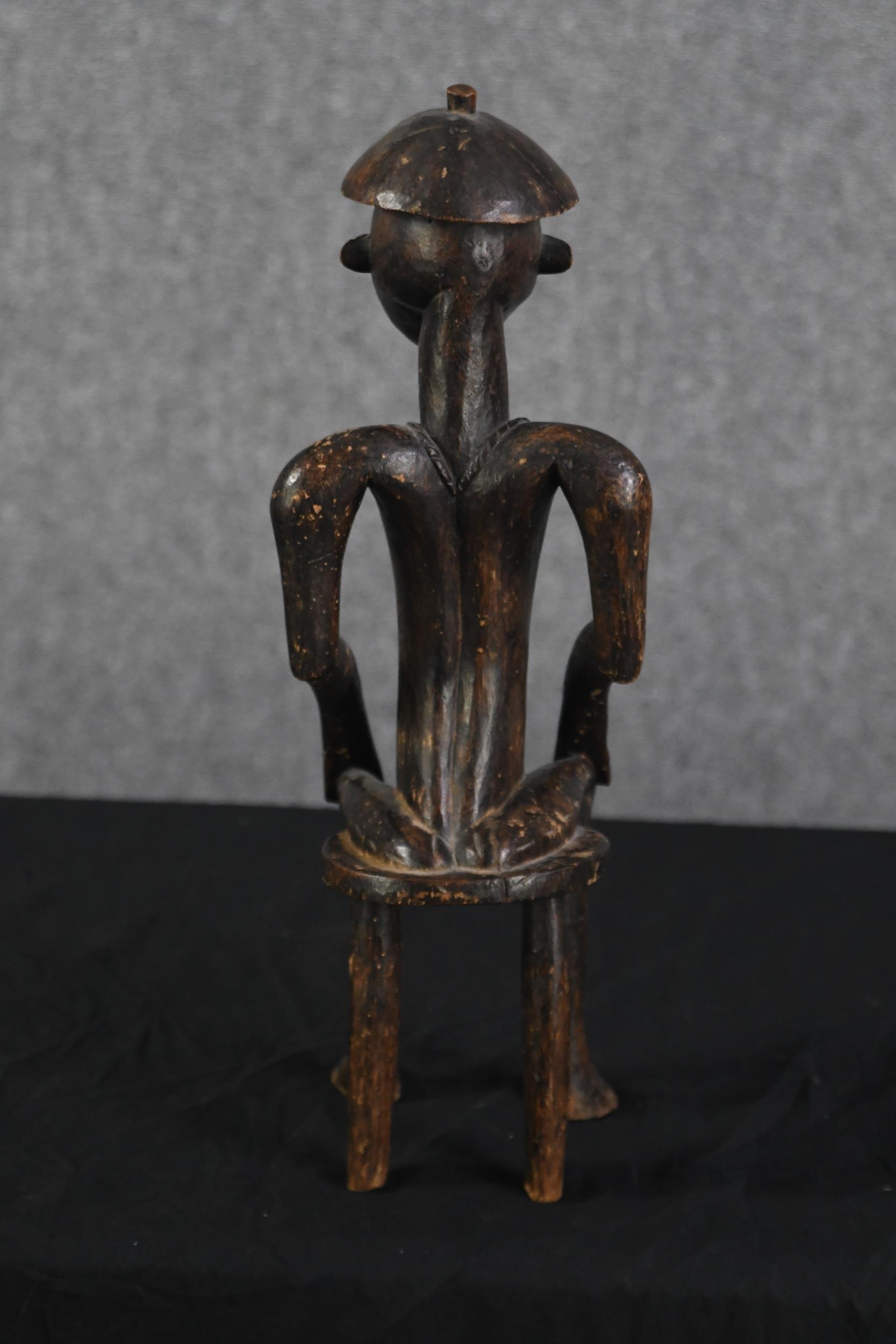 A carved hardwood figure. Tribal Art. A seated man with a decorated chest. H.53 x W.15 x D.15 cm. - Image 3 of 3