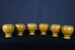 Six Chinese urns in a yellow glaze. With raised dragon design barely visible within the glaze.