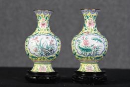 A pair of Chinese vases in a floral decoration on hardwood stands. With gilt finish to the lip. H.23