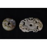 Two Chinese bi disks made of jade and soapstone. The jade design features what looks like tigers and