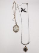 A collection of a silver locket, necklace and brooch. The modernist necklace set with a sapphire