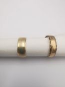 Two 9ct yellow gold wedding bands, one with engraved detailing to the border. Weight 5.64g Ring