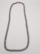 A black cultured pearl knotted necklace with 10ct yellow gold clasp. The necklace is comprised of