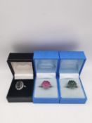 Three silver gem set rings, a ruby cluster ring, an emerald cluster ring and a white metal garnet