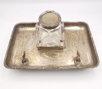 A sterling silver inkwell and pen stand with ribbon detailing to the edge, button feet and shield