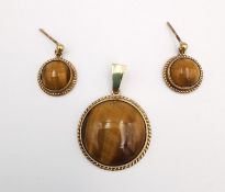 A yellow metal tigers eye cabochon set pendant and matching earrings with rope design to the
