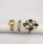 Three gem set silver rings, a Citrine flanked solitaire and matching five stone ring and a garnet,